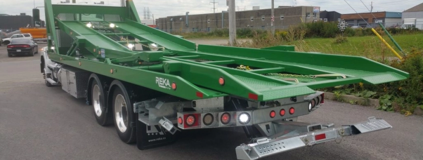 Camion porte-voiture vert sur route